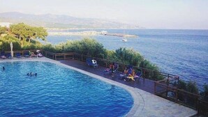 Zona de piscina con vistas al mar y montañas a lo lejos.