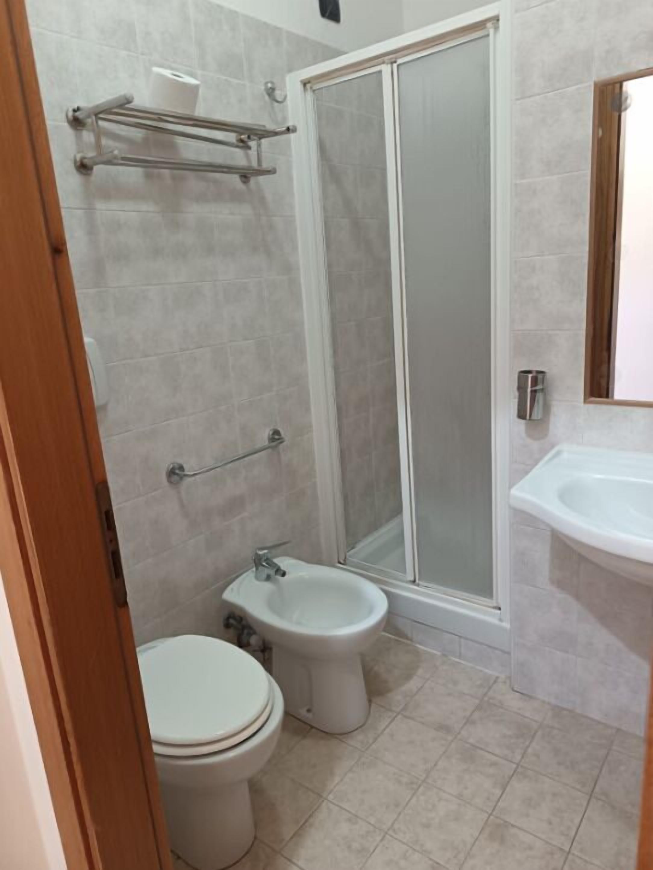 Et badeværelse med toilet, bidet og en bruseniche.