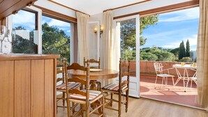 A wooden dining table with chairs, a bar counter, and a view of a balcony with outdoor seating. - Studio in Spain near Beach & Mountain Views (Calella de Palafrugell, Llafranc)