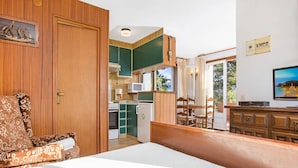 A room with a bed, a wooden chair, a small kitchenette, and a television. - Studio in Spain near Beach & Mountain Views (Calella de Palafrugell, Llafranc)