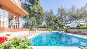 A swimming pool with clear blue water, surrounded by greenery and a building with a balcony. - Studio in Spain near Beach & Mountain Views (Calella de Palafrugell, Llafranc)