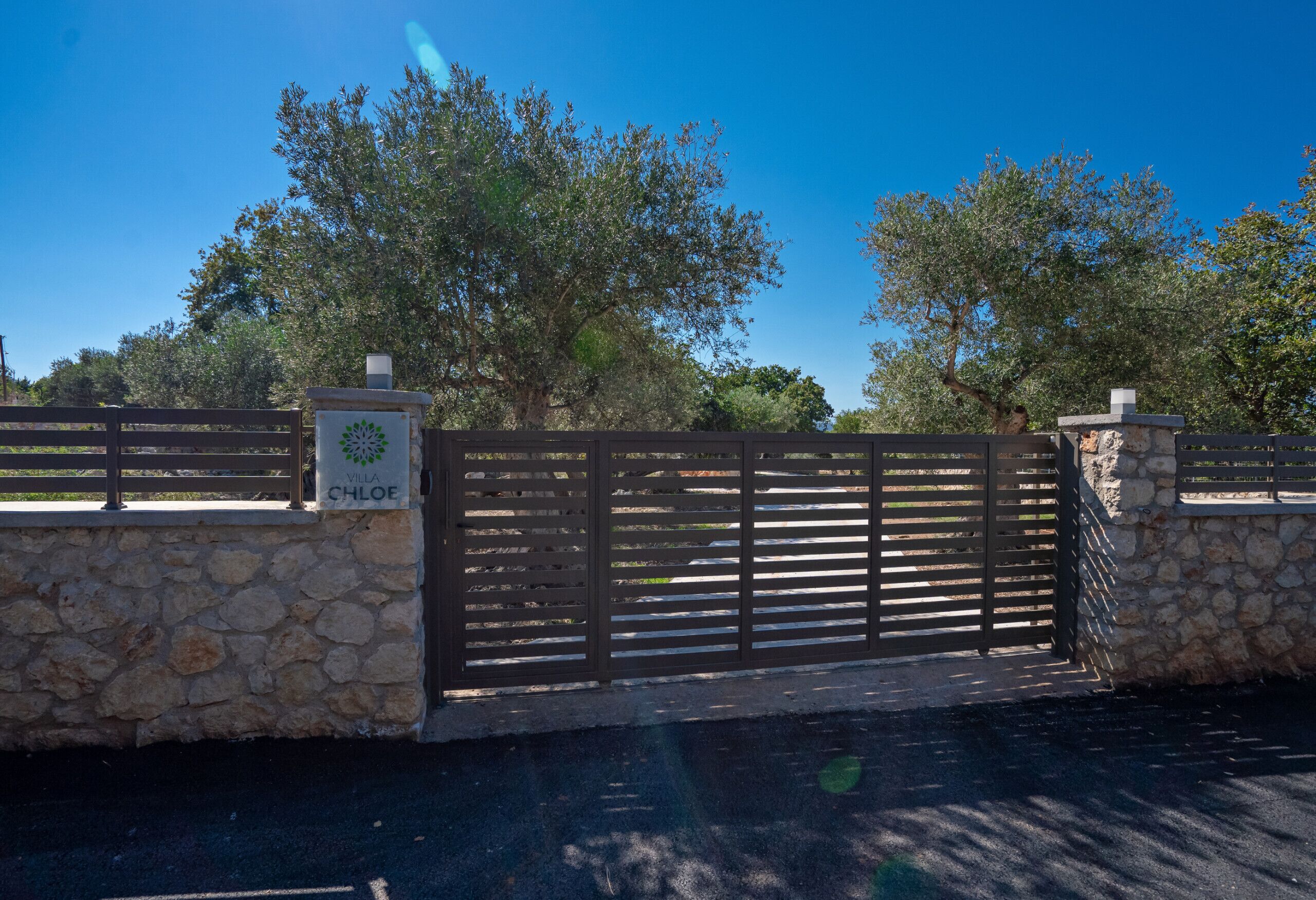 A gated entrance with a stone wall and a sign reading "Villa Chloe."