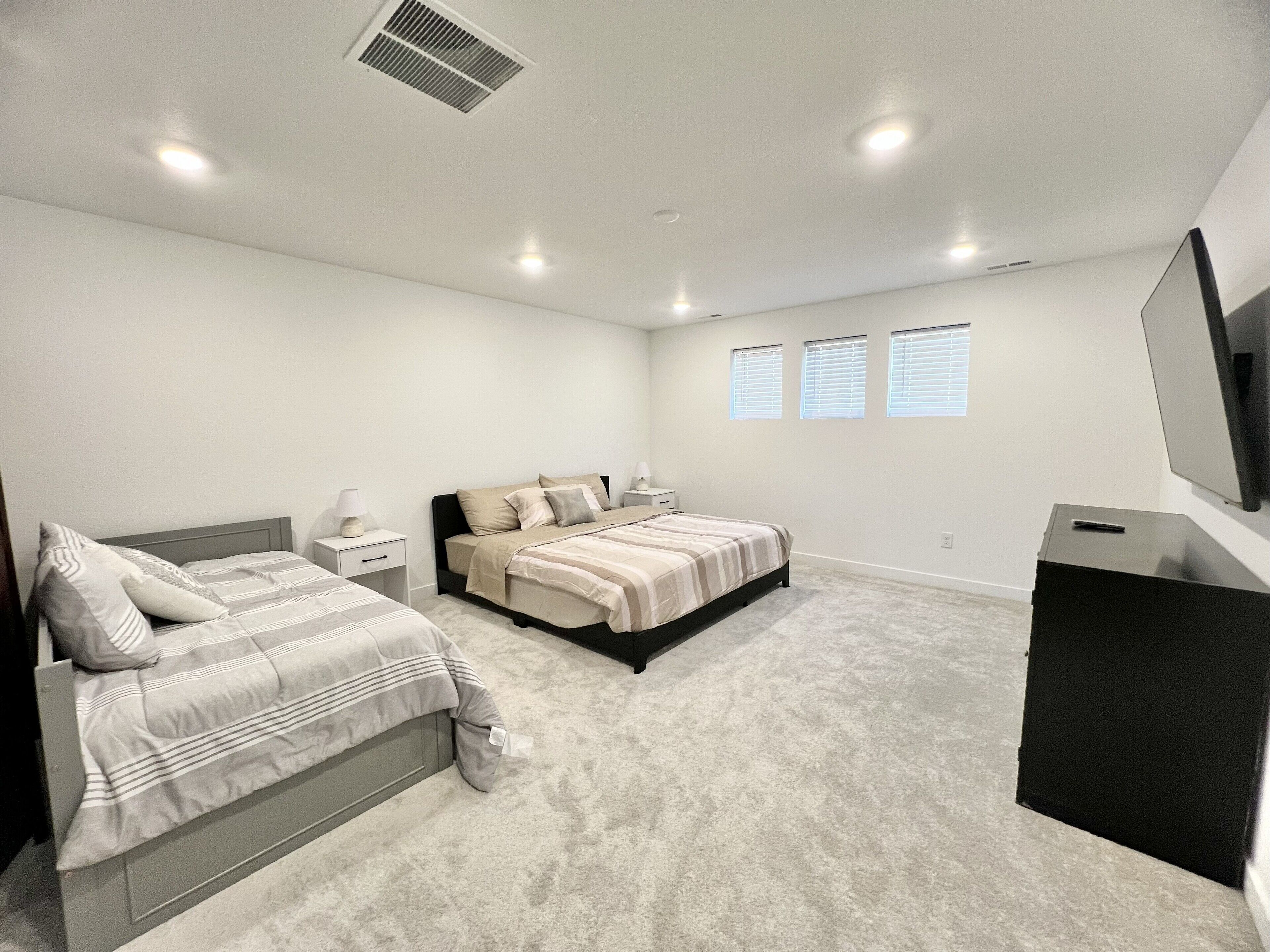 Quarto com duas camas, televisão e escrivaninha.