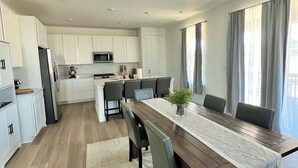 A modern kitchen with white cabinets, a stainless steel refrigerator, and a microwave. - New spacious 4-bedroom house in serene Brighton with cool AC and fast Wi-Fi. (Brighton)