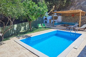 Ein Schwimmbecken mit Holzterrasse, Liegestühlen und einer Pergola.