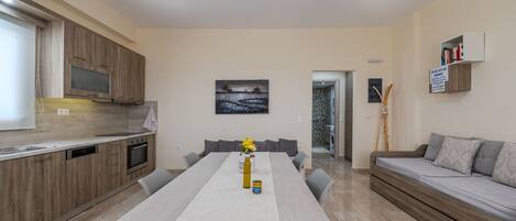A modern kitchen with wooden cabinets, a dining table with a white tablecloth, and a sofa with cushions.