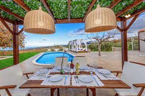 Ein Essbereich im Freien mit gedecktem Tisch, mit Blick auf einen Pool und eine schöne Landschaft.