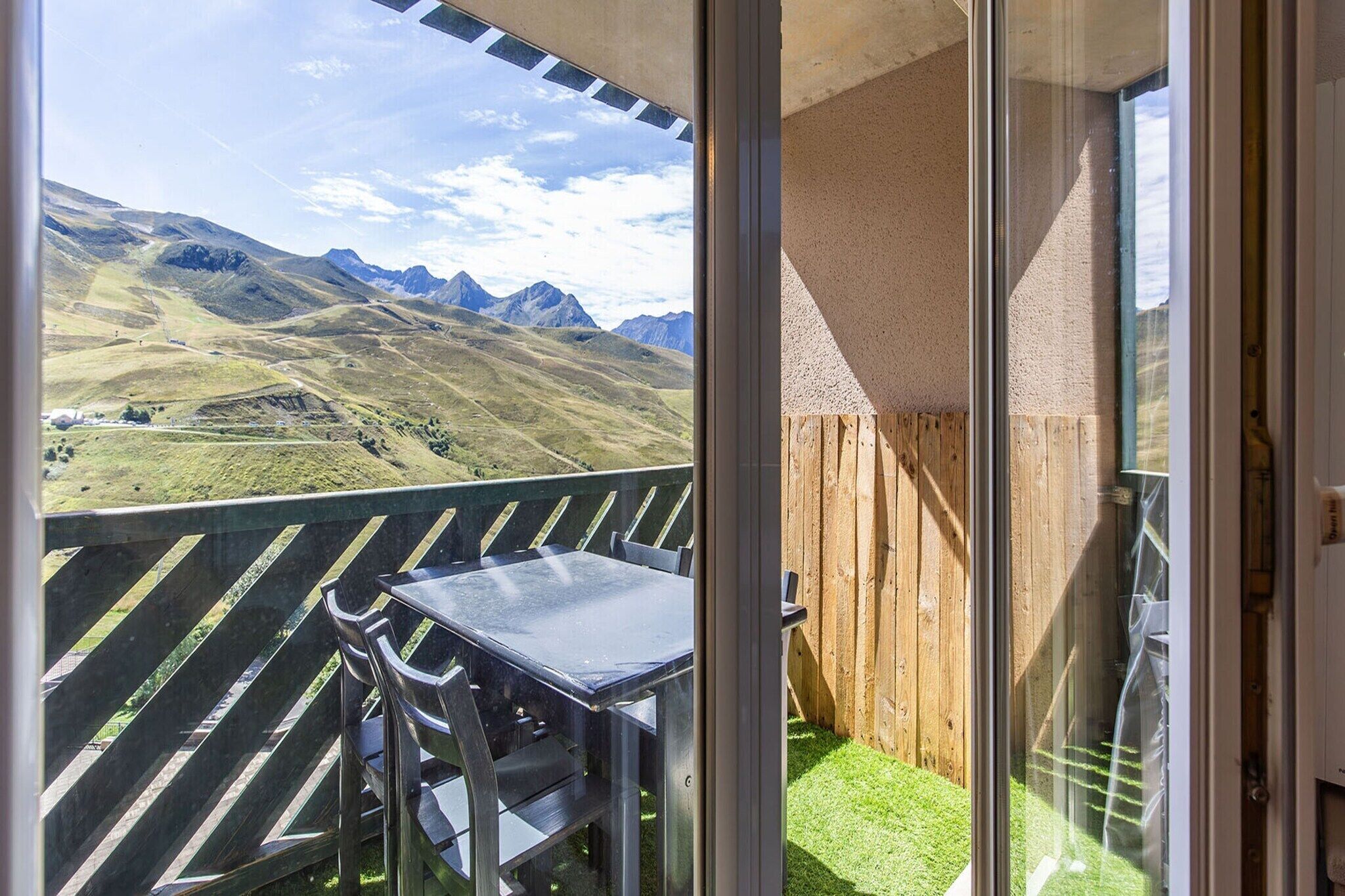 Ein Balkon mit Tisch und Stühlen, der Blick auf eine Berglandschaft bietet.