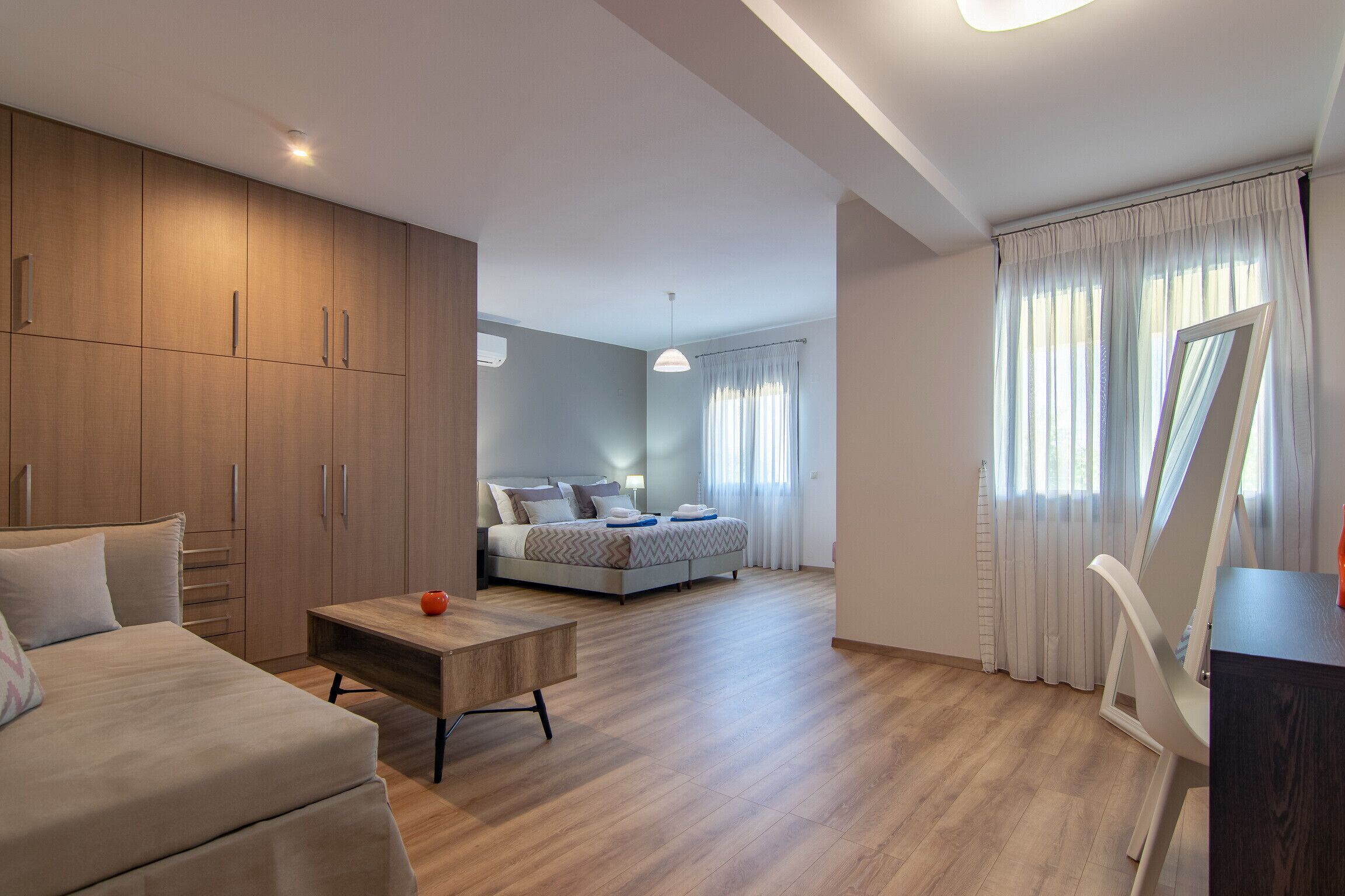 Ein modernes Schlafzimmer mit großem Kleiderschrank, einem Bett, einem Schreibtisch und einem Esstisch.