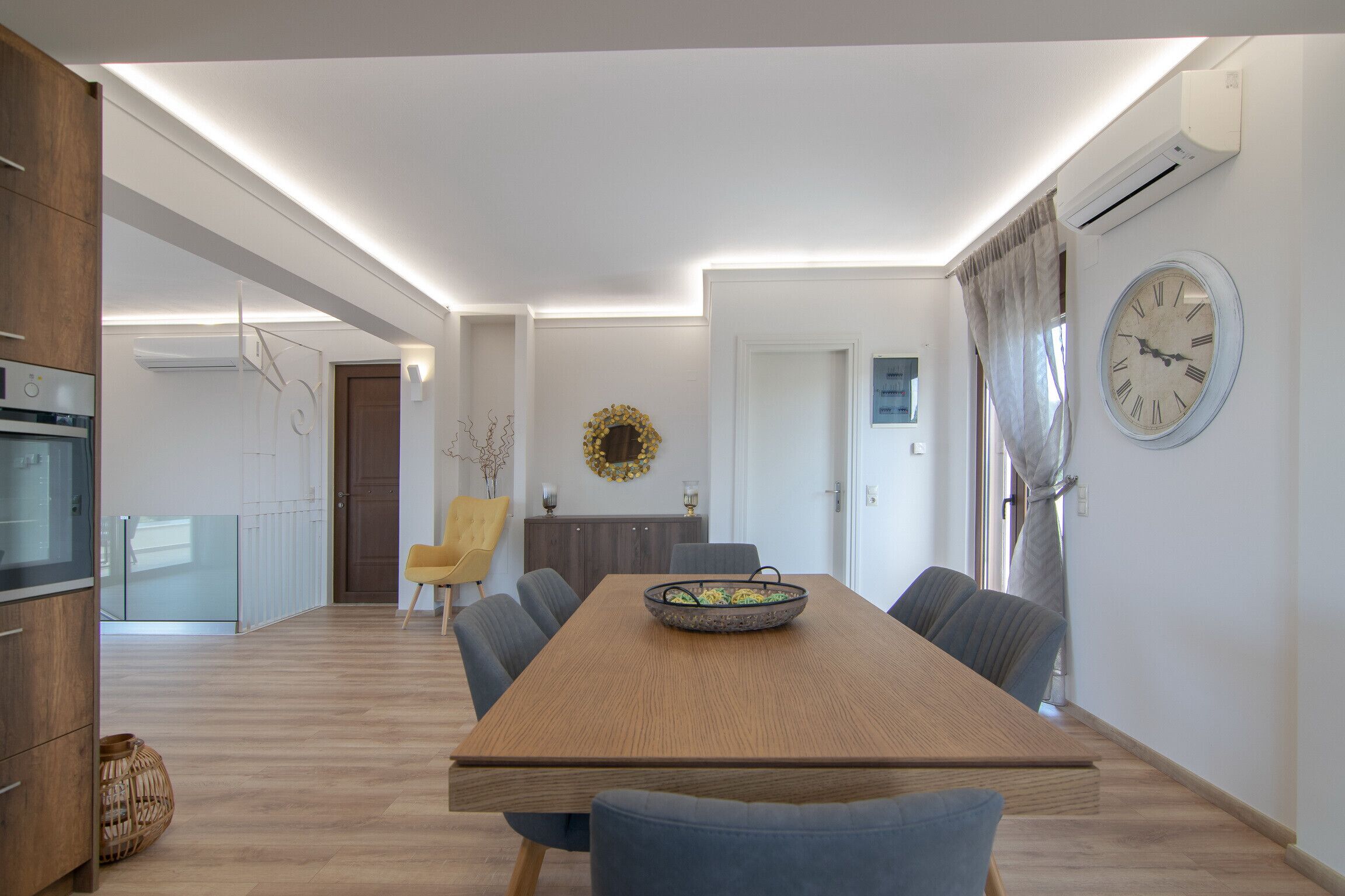 Un espace repas moderne avec une table en bois, des chaises et une horloge murale.