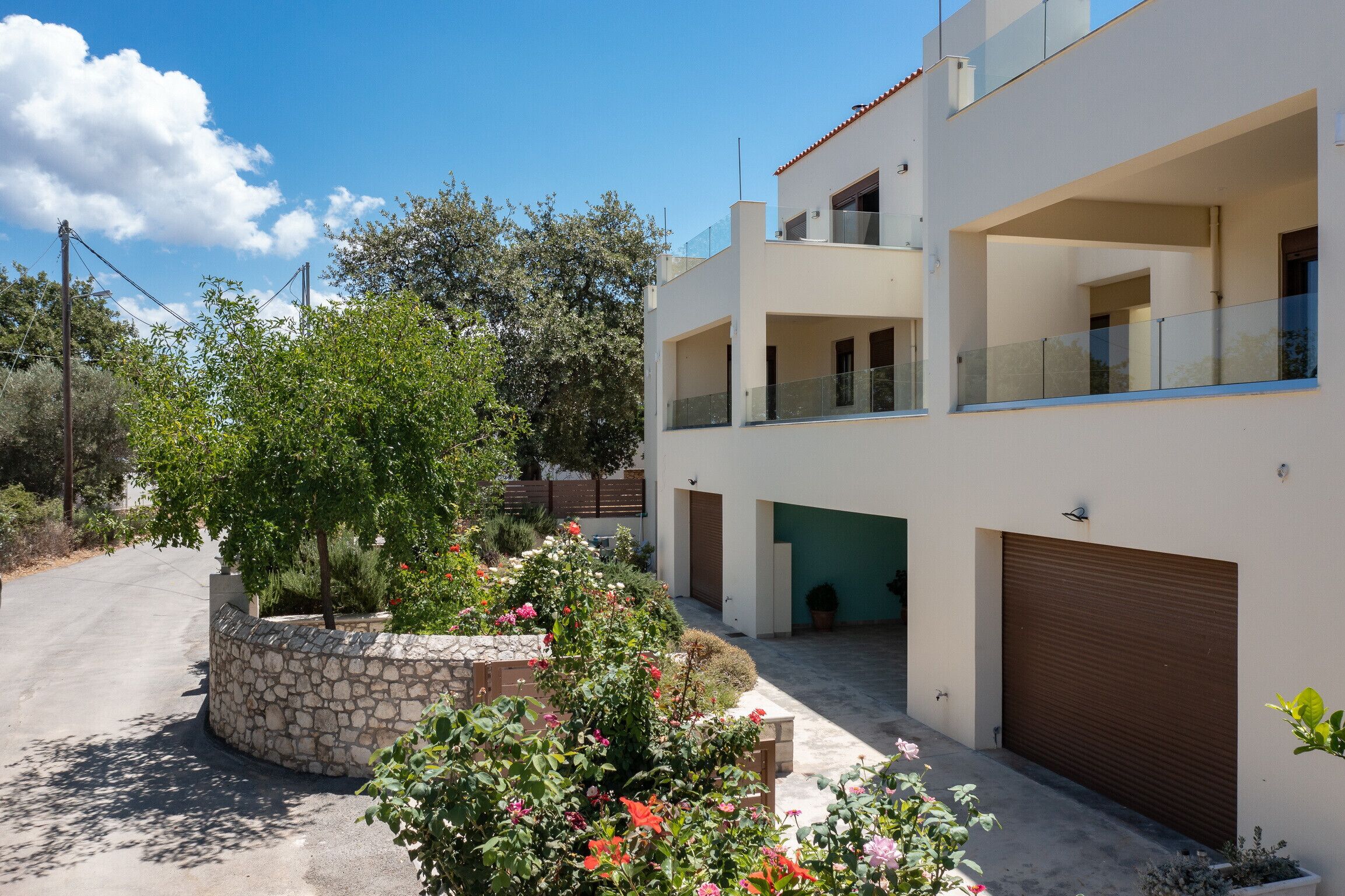 A modern two-story house with a stone garden, a garage, and a balcony.