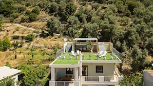 A two-story building with a rooftop terrace, a balcony, and a view of a hillside. - Stefanakos House (Agios Vasileios)