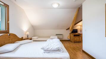 Ein Schlafzimmer mit einem großen Bett, einem kleineren Bett, einem Schreibtisch und einem Fenster.