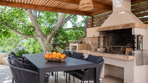 Een terras buiten met een tafel, stoelen en een ingebouwde barbecue.