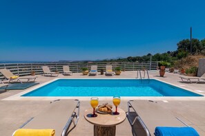 A pool with lounge chairs and a table with drinks and snacks. - Haravgi Villa (Rethymno)