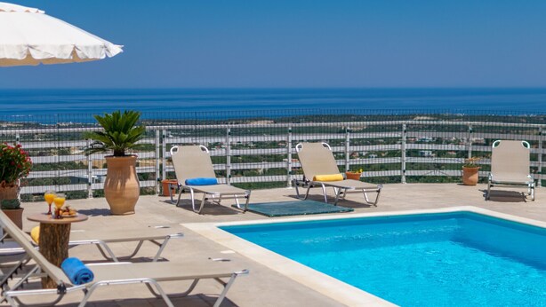 Un área de piscina con sillones de descanso y vista al océano.