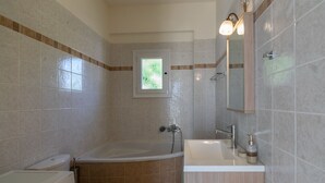 Un baño con bañera, inodoro, lavabo y espejo.
