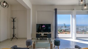Una sala de estar moderna con un televisor de pantalla plana, una mesa de centro de vidrio y un sofá.