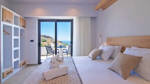 Ein Schlafzimmer mit einem großen Bett, einem hölzernen Kopfteil, einer eingebauten Garderobe und einem Balkon mit Tisch und Stühlen.