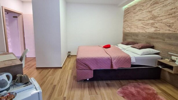 Un dormitorio moderno con cama, mesita de noche y un pequeño escritorio con silla.