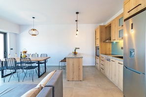 A modern kitchen with wooden cabinets, a stainless steel refrigerator, and a central island. - Petasos Villa 2 (Agios Vasileios)