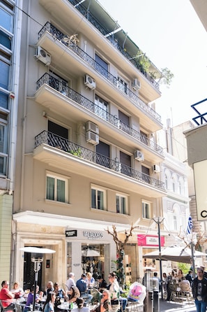 A multi-story building with balconies, air conditioning units, and a café at the ground level. - Athens Heart Gem Lux Apartment (Athens)