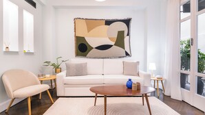 A modern living room with a white sofa, a round coffee table, and a large abstract painting on the wall. - Athens Heart Gem Lux Apartment (Athens)