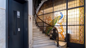 A staircase with a glass door featuring a peacock design, a black door with a vent, and a handrail. - Athens Heart Gem Lux Apartment (Athens)