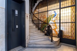 A staircase with a glass door featuring a peacock design, a black door with a vent, and a handrail. - Athens Heart Gem Lux Apartment (Athens)