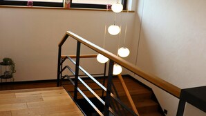Un escalier en bois avec une rampe noire et des lampes sphériques suspendues.