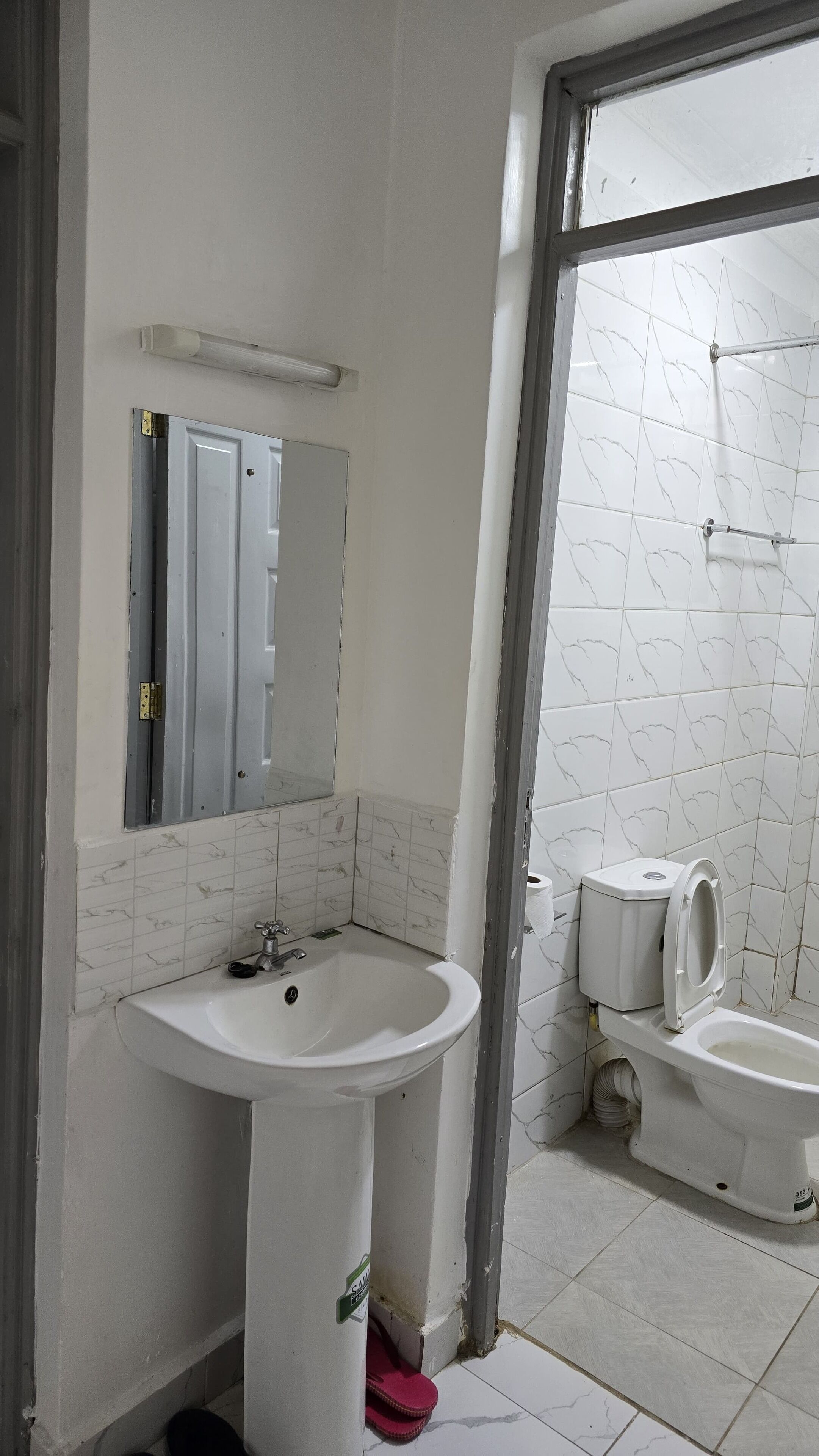 Un baño con lavamanos, espejo, inodoro y zona de ducha.