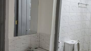 Un baño con lavamanos, espejo, inodoro y zona de ducha.