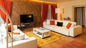 Un salon moderne avec un canapé blanc, des rideaux rouges et blancs, un téléviseur à écran plat et une lampe.