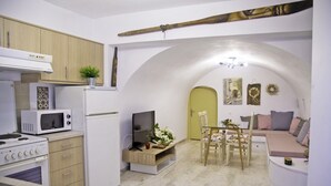 A compact kitchen with modern appliances, a dining area with a sofa, and a small seating space. - Areopolis Art Apartment (East Mani)
