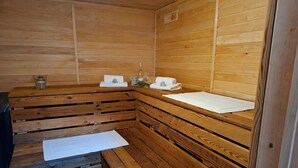 Una sauna de madera con bancos, toallas y una botella de vino.