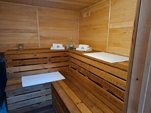 Un sauna en bois avec des bancs, des serviettes et une bouteille de vin.