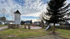 Un parque infantil con un tobogán, una estructura para escalar y un camino de ladrillos.
