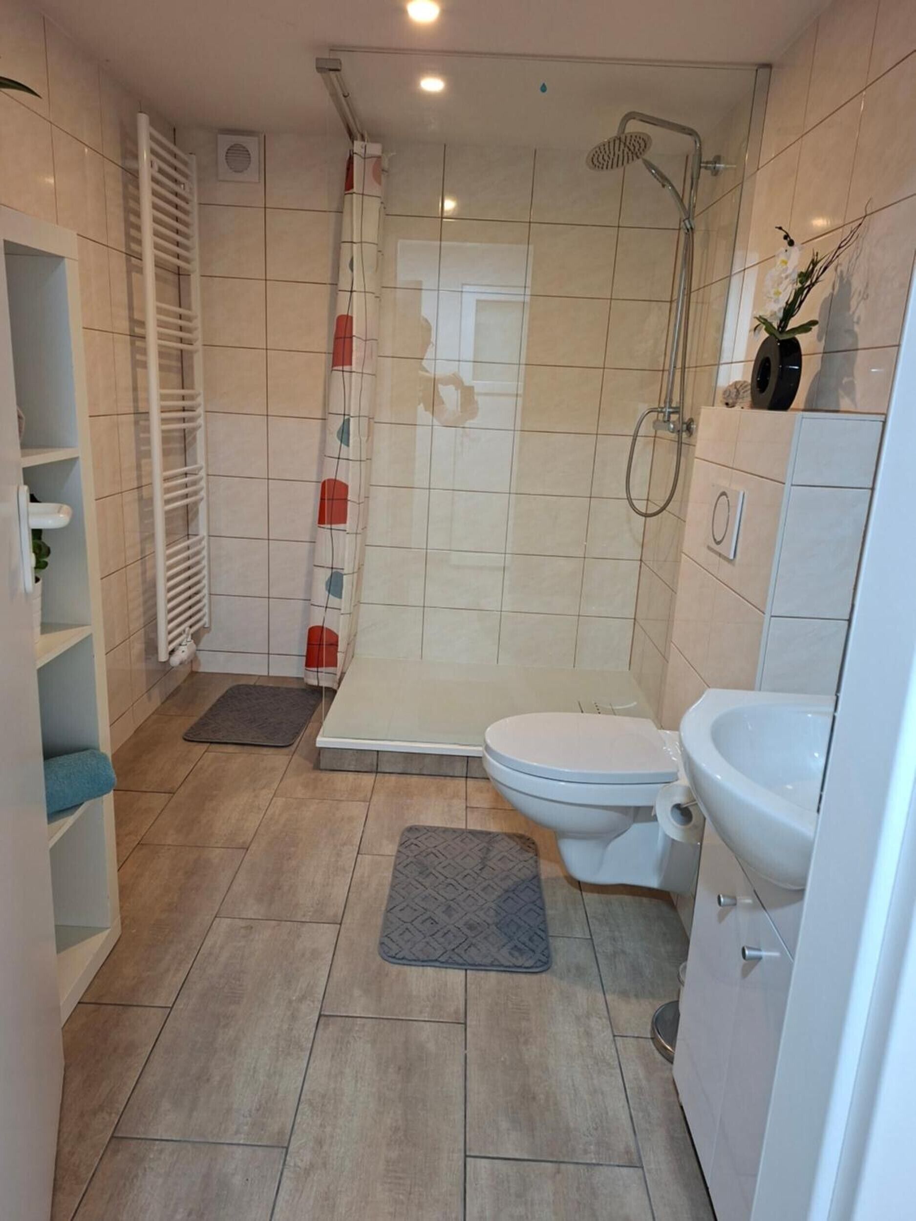 A bathroom with a shower, toilet, sink, and a towel rack.