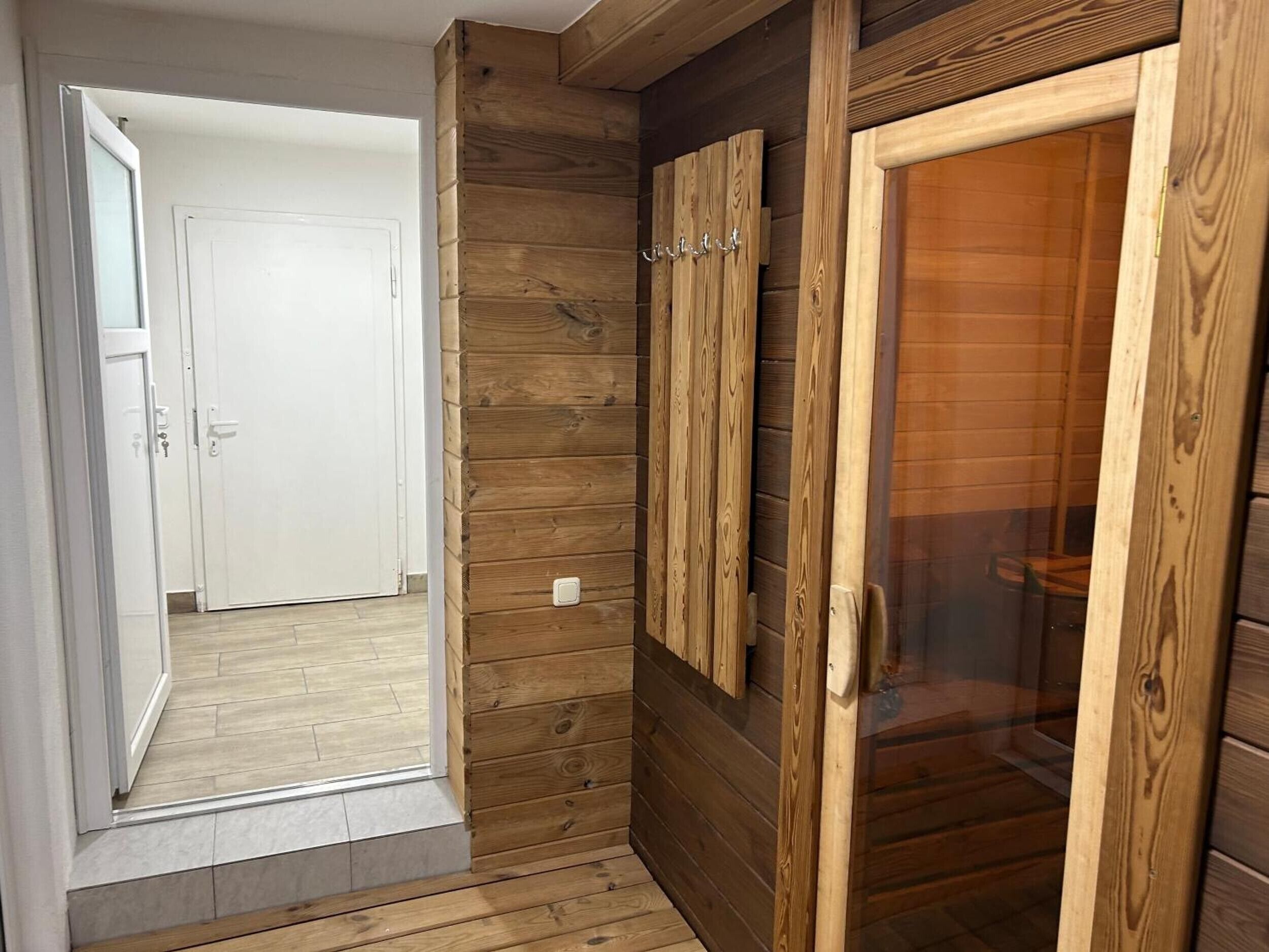 A hallway with wooden paneling, a white door, and a glass door leading to a room.