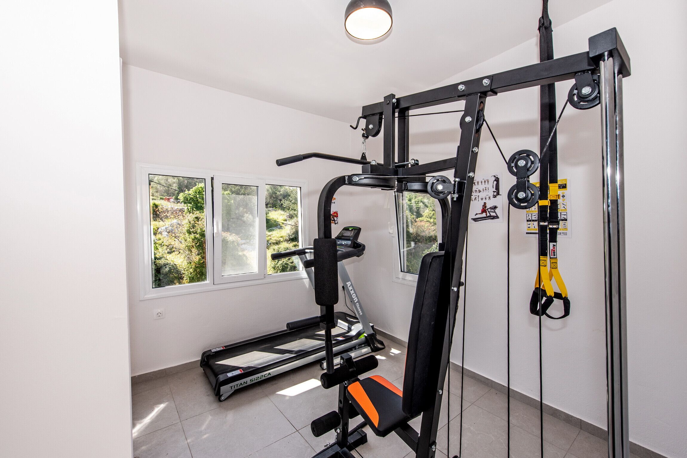 Een fitnessruimte met een loopband, een gewichtbank en diverse trainingsapparaten.