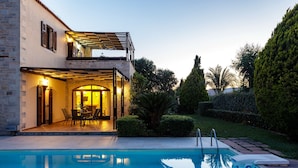 Uma casa de dois andares com piscina, área de estar externa e um jardim bem cuidado.