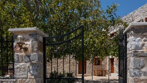 A stone gate with a metal fence, a wooden bench, and a stone building with a door and window. - Archodiko Villa Imbros (Sfakia)