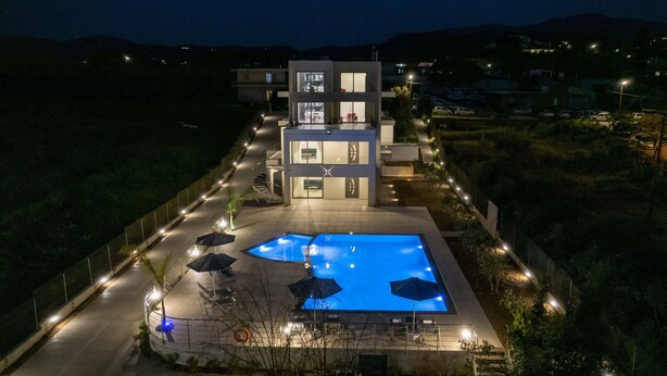 Een modern gebouw met een zwembad, terras en een goed verlichte ingang.