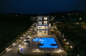 Un edificio moderno con piscina, zona de estar exterior y entrada bien iluminada.