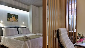 Habitación de hotel con cama, un cuadro, una silla de madera y una mesa con un florero.