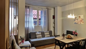 Un comedor con mesa de madera, sillas, un sofá y una ventana con cortinas.