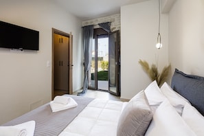 A bedroom with a bed, a television, a sliding glass door, and a wall-mounted light fixture. - Stone Project Villa (Rethymno)