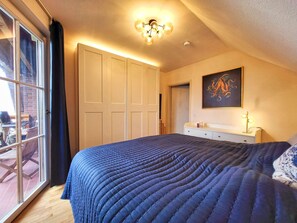 A bedroom with a large bed, a ceiling light fixture, a door, and a window. - Apartment Blick auf Vilm - quietly located apartment with sea view - (Putbus)