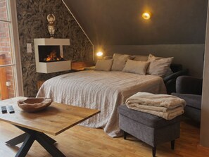 A bedroom with a bed, bedside table, and a fireplace. - Vue sur Vilm Apartment - quiet apartment with a view of the sea - (Putbus)