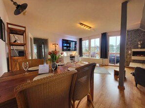 A dining area with a wooden table, wicker chairs, and a vase of flowers. - Apartment Blick auf Vilm - quietly located apartment with sea view - (Putbus)
